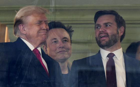 In this picture taken through a window, from left, President-elect Donald Trump, Elon Musk and Vice President-elect JD Vance attend the NCAA college football game between Army and Navy at Northwest Stadium in Landover, Md., Dec. 14, 2024. (AP/Stephanie Scarbrough)